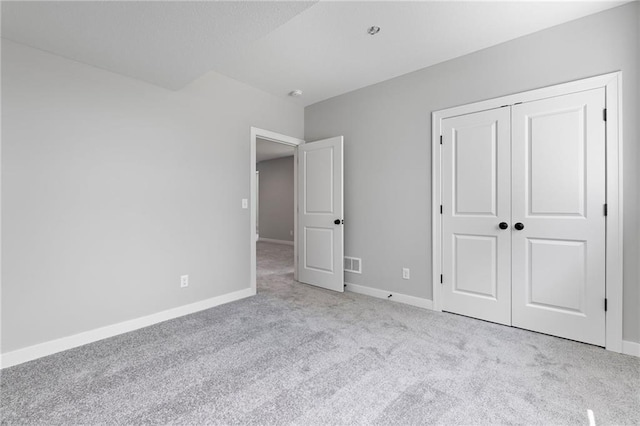 unfurnished bedroom featuring carpet floors, baseboards, visible vents, and a closet
