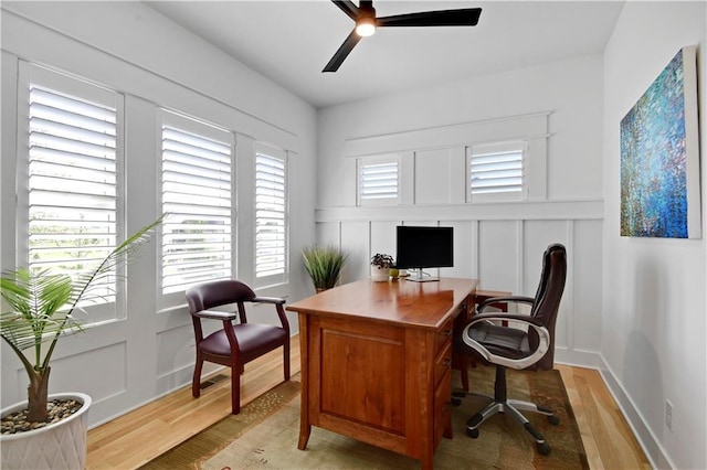 office area featuring a decorative wall, light wood-style flooring, and ceiling fan