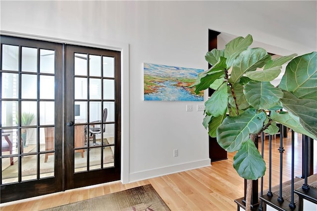 doorway featuring french doors, baseboards, and wood finished floors