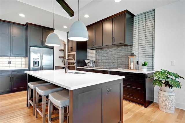 kitchen with stainless steel appliances, a sink, backsplash, light countertops, and recessed lighting