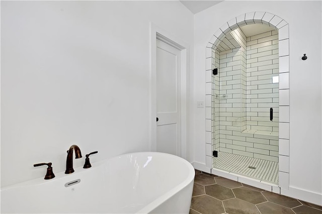 full bath featuring a shower stall, tile patterned floors, a freestanding tub, and baseboards