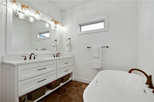bathroom with a freestanding bath, double vanity, tile patterned floors, and baseboards