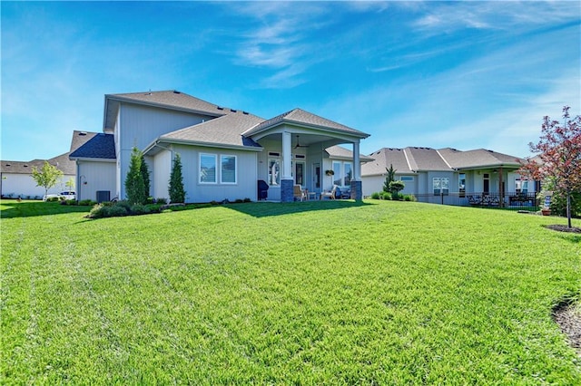 back of house featuring a lawn, a ceiling fan, central AC, and roof with shingles