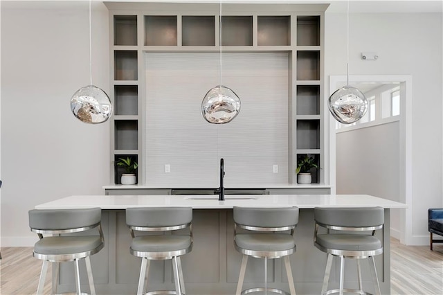 bar featuring a sink, baseboards, and light wood-style flooring