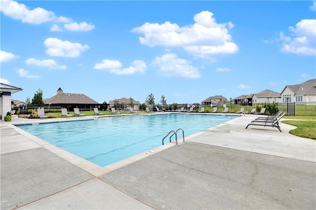 community pool featuring fence, a patio area, and a residential view