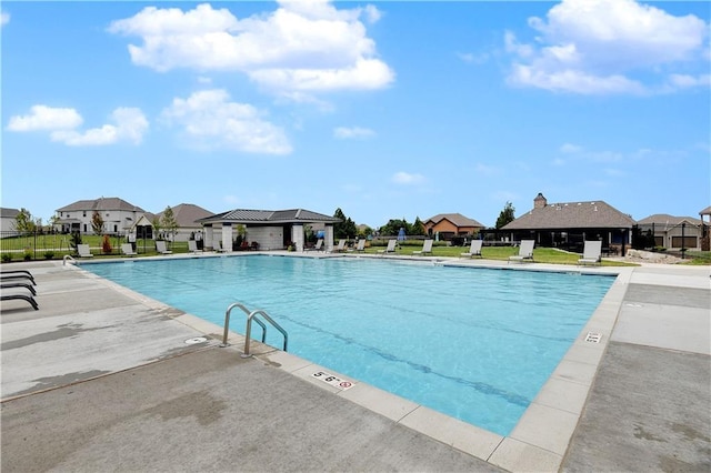 community pool with fence, a residential view, and a patio