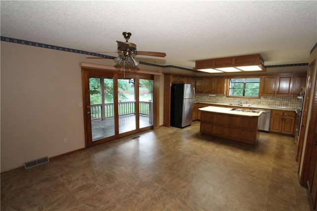 6726 Mill Creek Rd, Shawnee, KS 66217 - kitchen featuring stainless steel appliances, a textured ceiling, a ceiling fan, a kitchen island, and light countertops
