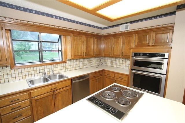 6726 Mill Creek Rd, Shawnee, KS 66217 - kitchen featuring appliances with stainless steel finishes, brown cabinetry, light countertops, a sink, and tasteful backsplash