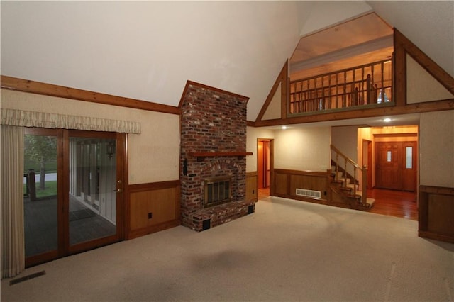 6726 Mill Creek Rd, Shawnee, KS 66217 - unfurnished living room featuring a wainscoted wall, high vaulted ceiling, stairs, carpet flooring, and a brick fireplace