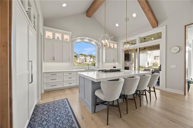 11201 W 169th St, Overland Park, KS 66221 - kitchen featuring beamed ceiling, a sink, a kitchen island, healthy amount of natural light, and white cabinetry