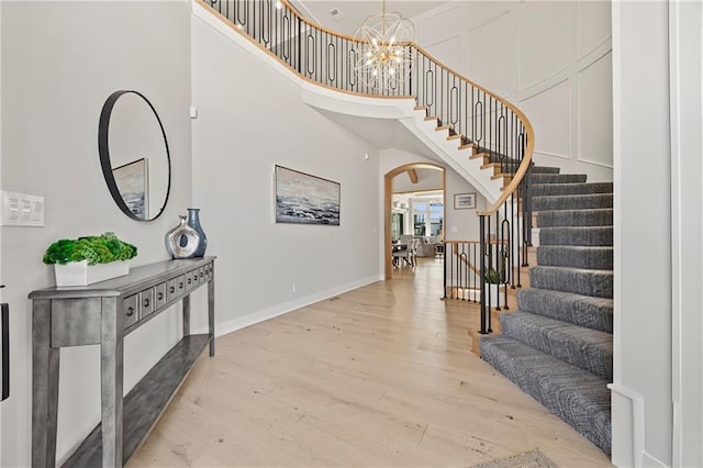 11201 W 169th St, Overland Park, KS 66221 - entrance foyer featuring arched walkways, light wood-style floors, stairs, a chandelier, and a high ceiling