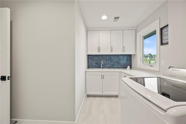 11201 W 169th St, Overland Park, KS 66221 - kitchen with white cabinets, a sink, decorative backsplash, light countertops, and baseboards