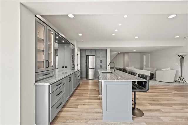 11201 W 169th St, Overland Park, KS 66221 - kitchen with gray cabinetry, stainless steel fridge, a kitchen bar, light wood finished floors, and a sink