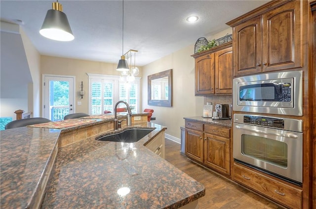 3536 SW Dana Ave E, Lees Summit, MO 64082 - kitchen featuring appliances with stainless steel finishes, a sink, dark wood-type flooring, pendant lighting, and baseboards