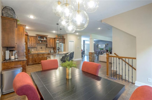 3536 SW Dana Ave E, Lees Summit, MO 64082 - dining area with baseboards, a chandelier, decorative columns, recessed lighting, and light wood-type flooring