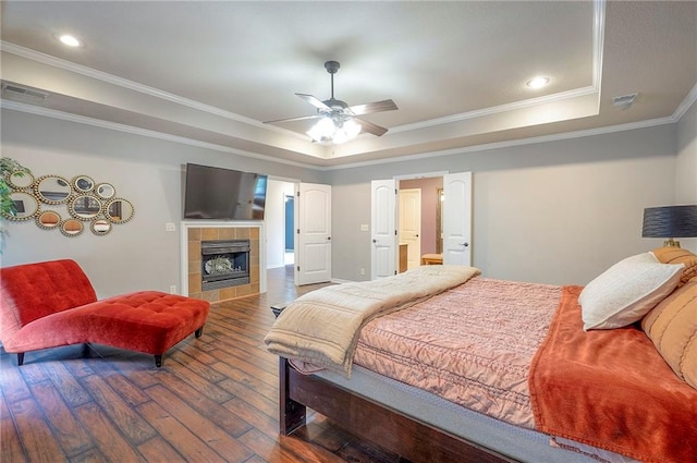 3536 SW Dana Ave E, Lees Summit, MO 64082 - bedroom featuring a tray ceiling, hardwood / wood-style flooring, crown molding, a tiled fireplace, and recessed lighting