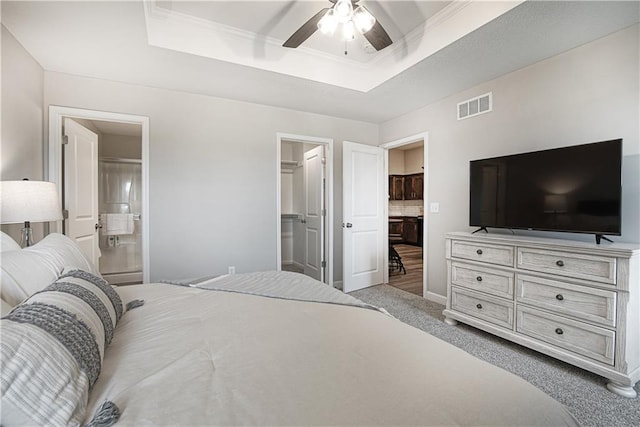 bedroom with a raised ceiling, a walk in closet, connected bathroom, and visible vents