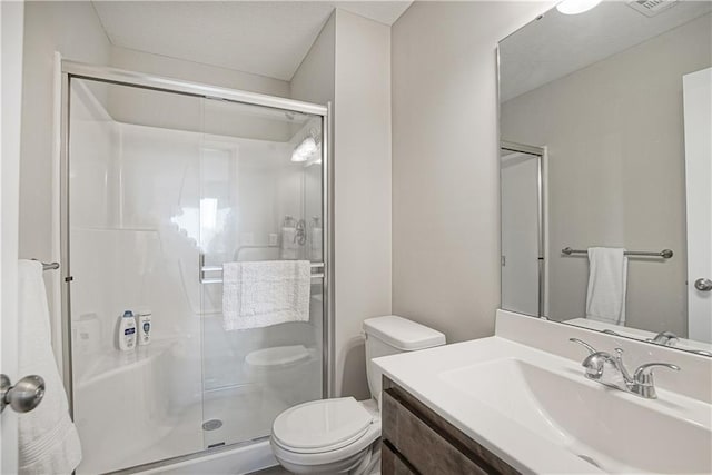 bathroom featuring vanity, a stall shower, and toilet