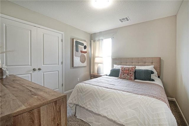 carpeted bedroom featuring baseboards, a textured ceiling, visible vents, and a closet