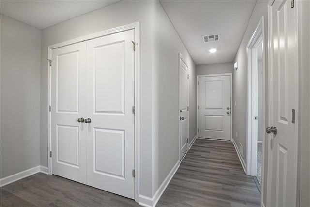 hallway featuring baseboards, visible vents, and dark wood-style floors