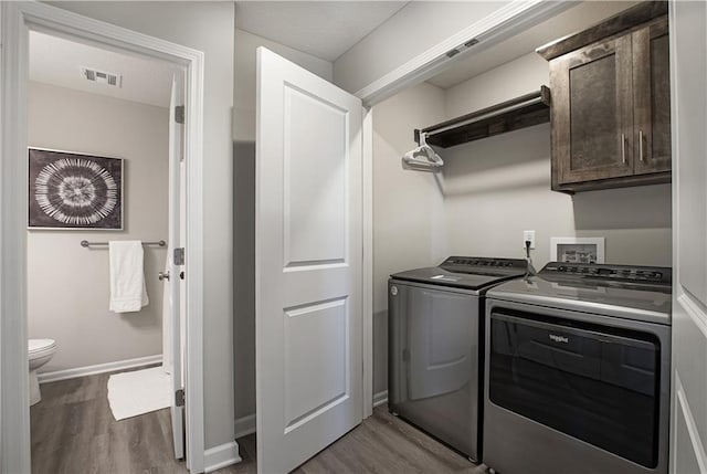 washroom featuring visible vents, washing machine and dryer, cabinet space, and dark wood-type flooring