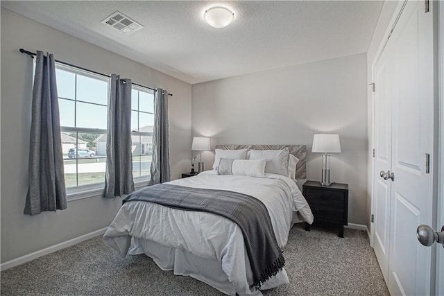 bedroom with carpet flooring, a textured ceiling, baseboards, and visible vents
