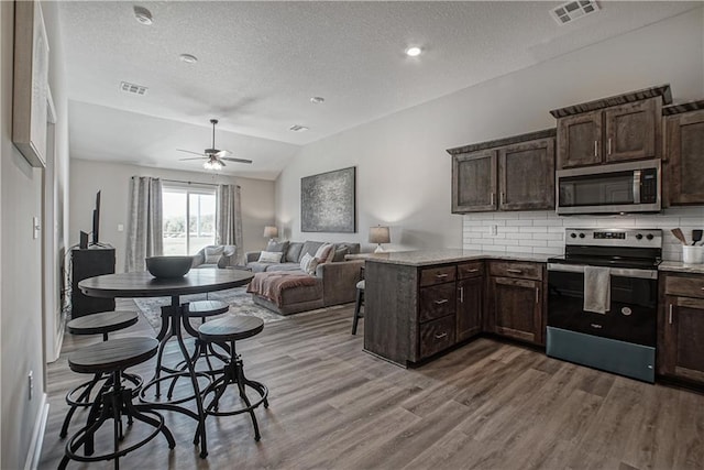 kitchen with visible vents, wood finished floors, dark brown cabinets, a textured ceiling, and stainless steel appliances