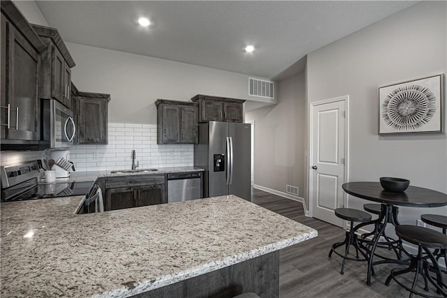 kitchen featuring visible vents, decorative backsplash, light stone counters, a sink, and appliances with stainless steel finishes