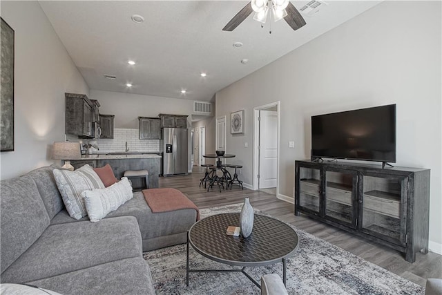 living area with a ceiling fan, visible vents, wood finished floors, and recessed lighting