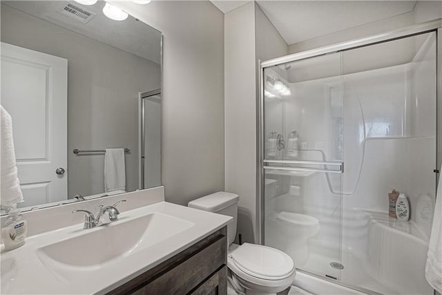 full bathroom with vanity, a stall shower, toilet, and visible vents