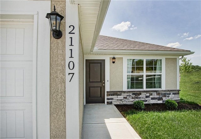 property entrance with a shingled roof, stucco siding, and stone siding
