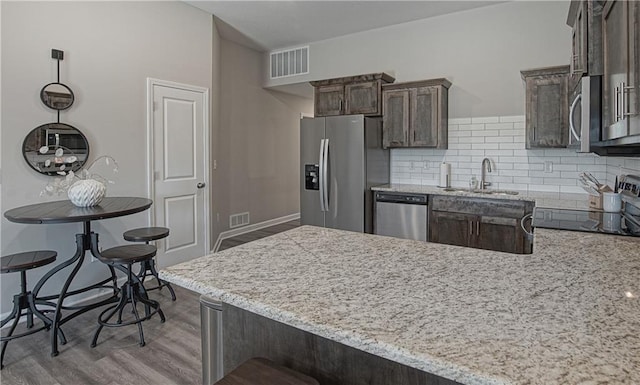 kitchen featuring a sink, light wood-style floors, stainless steel appliances, and visible vents