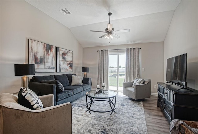 living area with visible vents, wood finished floors, baseboards, a ceiling fan, and vaulted ceiling