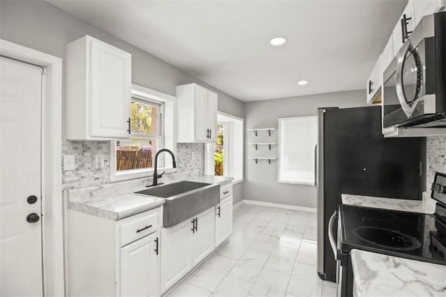 6101 Swope Pkwy, Kansas City, MO 64130 - kitchen featuring stainless steel microwave, electric range, light marble finish floors, white cabinetry, and tasteful backsplash