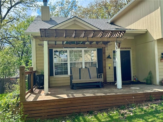 back of property with a pergola, a shingled roof, and a deck