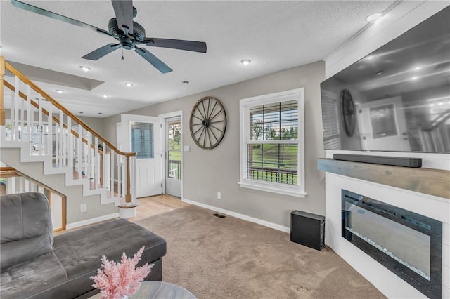 living room with stairs, a textured ceiling, visible vents, carpet floors, and baseboards