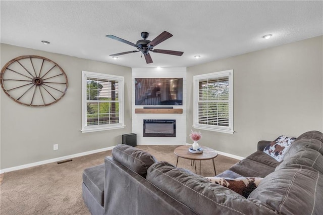 living area featuring carpet floors, baseboards, a ceiling fan, and visible vents