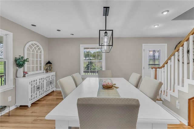dining area featuring baseboards, stairs, and light wood-style floors