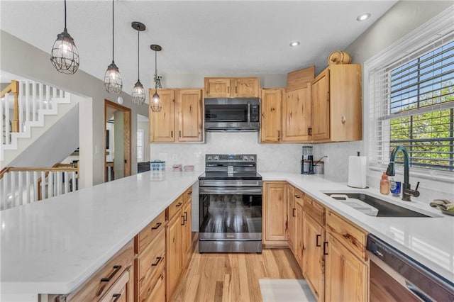 kitchen with a sink, stainless steel appliances, decorative backsplash, and light wood-style flooring