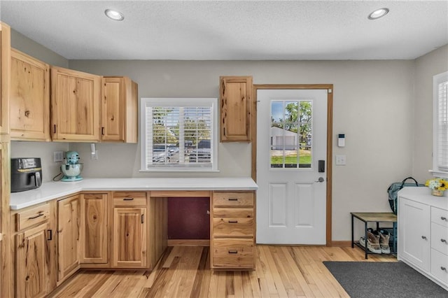 kitchen with a textured ceiling, light countertops, and light wood-type flooring