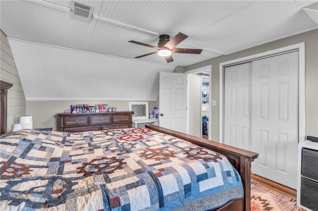 bedroom featuring lofted ceiling, a closet, visible vents, ceiling fan, and light wood-style flooring