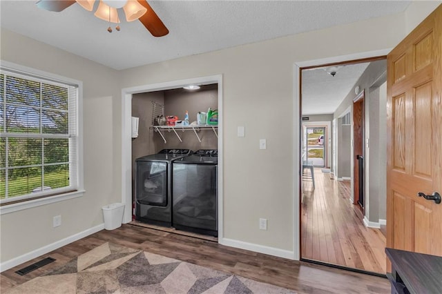 washroom featuring wood finished floors, visible vents, baseboards, ceiling fan, and independent washer and dryer