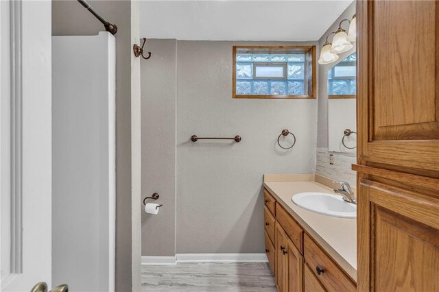 bathroom featuring baseboards, vanity, a textured wall, and wood finished floors