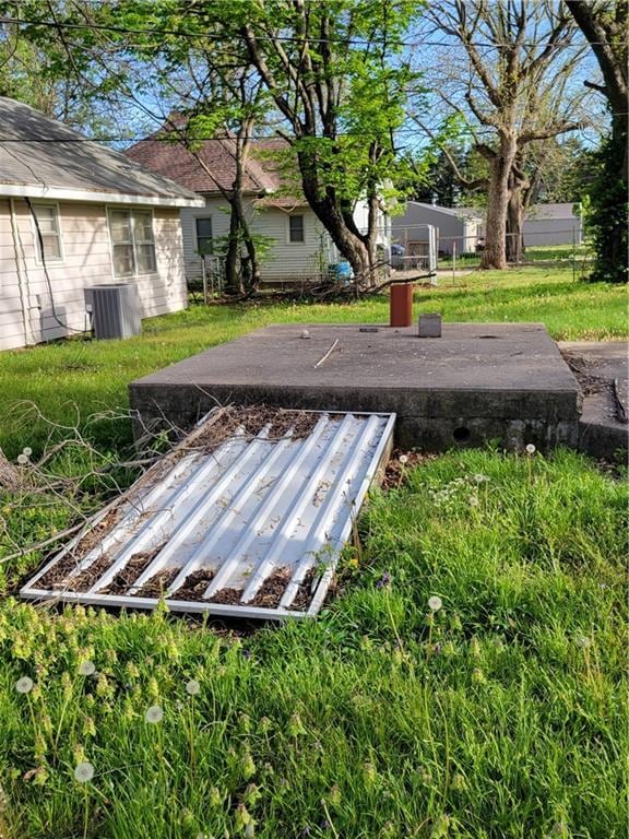 entry to storm shelter featuring fence, central AC unit, and a yard
