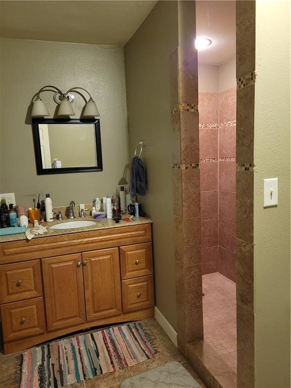 bathroom with vanity, tile patterned flooring, and a tile shower