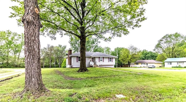 single story home featuring a chimney and a front yard