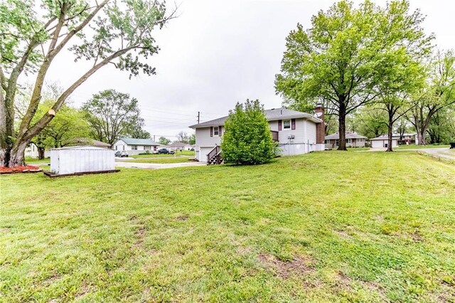 view of yard with an attached garage, an outdoor structure, driveway, and a storage unit