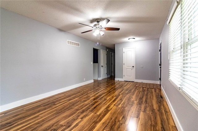 empty room featuring visible vents, a textured ceiling, ceiling fan, and wood finished floors