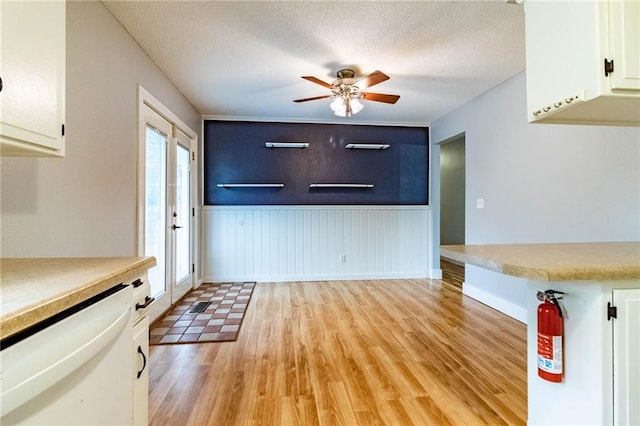 interior space with baseboards, ceiling fan, wainscoting, and light wood-type flooring