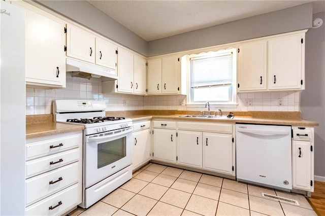 kitchen with decorative backsplash, visible vents, a sink, under cabinet range hood, and white appliances